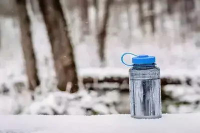 water bottle sitting on snow-covered log