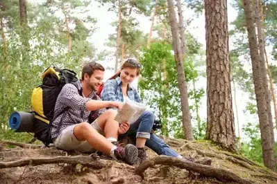 Happy couple reading a map on a hike together.